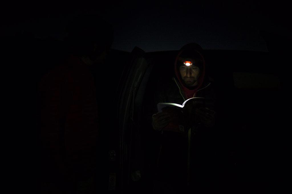 Man reading book with light of head lamp during night at Canyonlands National Park