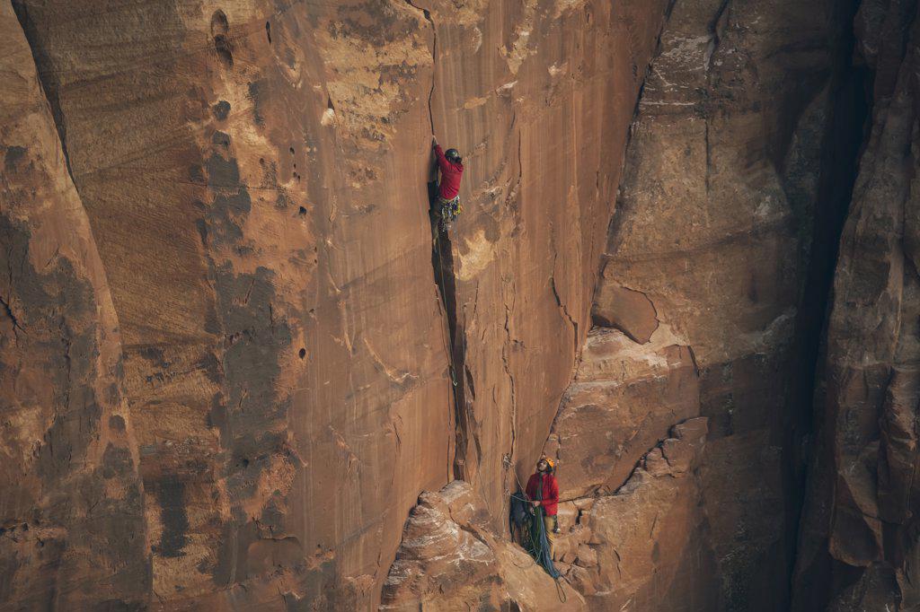 Men climbing rocky cliff at Canyonlands National Park