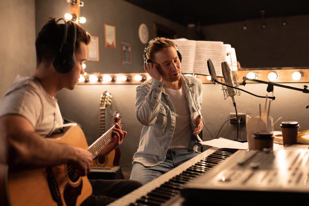 Men creating song in modern studio