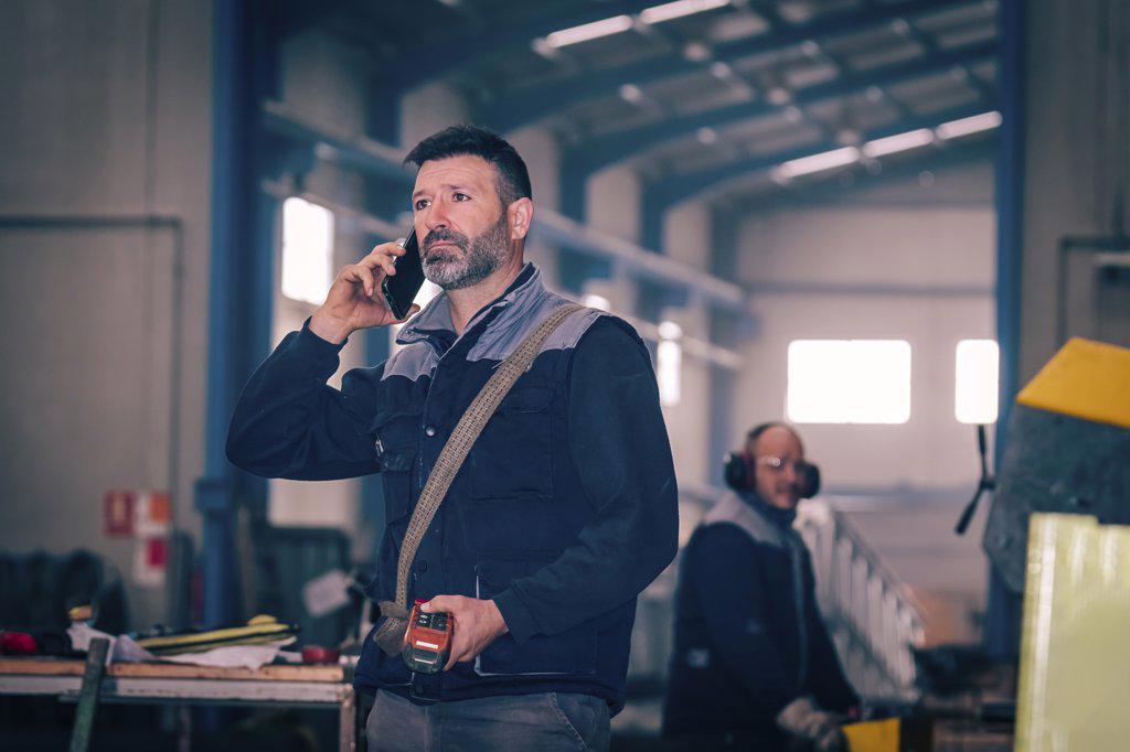 Man talking by telephone with the control of a bridge crane