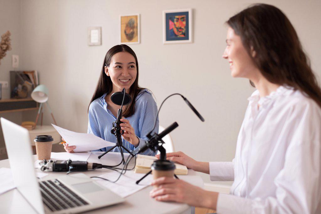 Multiracial women recording podcast in studio