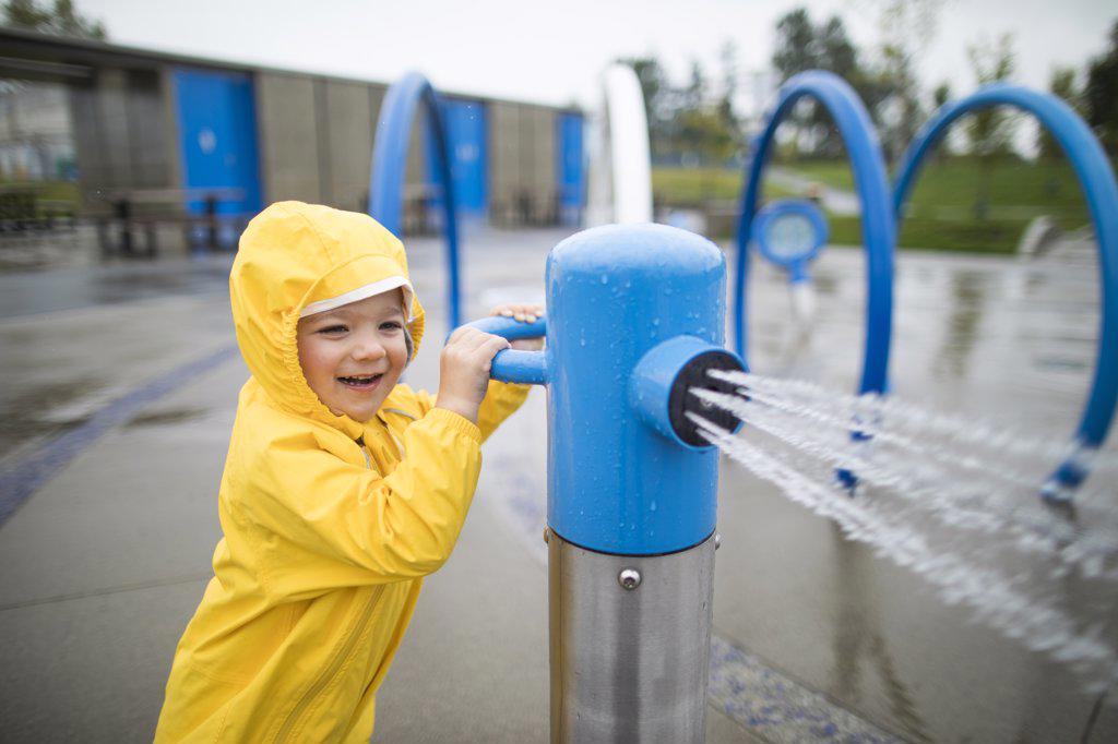 boy plays at the waterpark on a wet day.