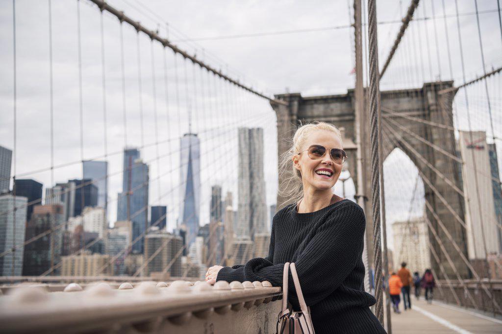 Delighted female tourist leaning on bridge railing