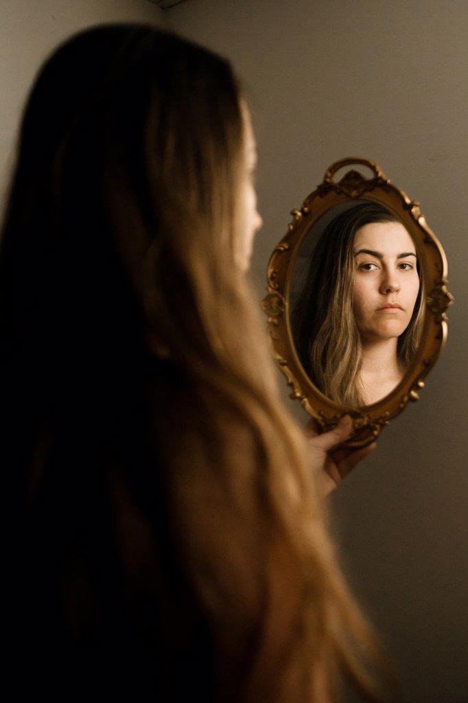 A woman looking at herself in a vintage mirror