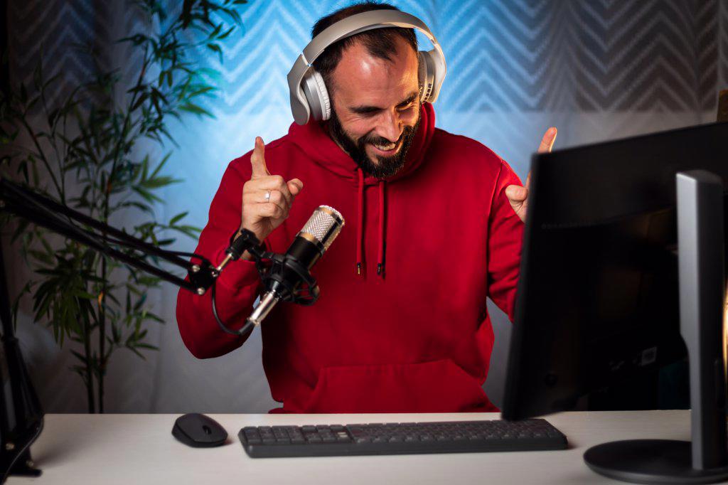 Content creator with headphones and microphone streaming a program online on the internet. Podcast presenter broadcasting on-air program. Content recording for internet program.