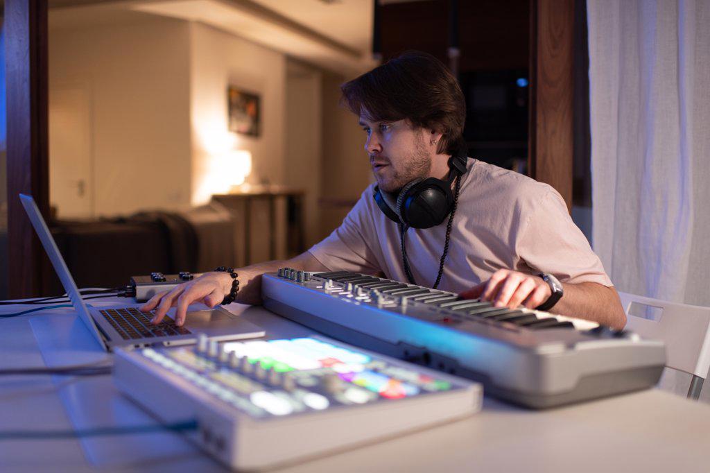 Male musician using laptop in home recording studio