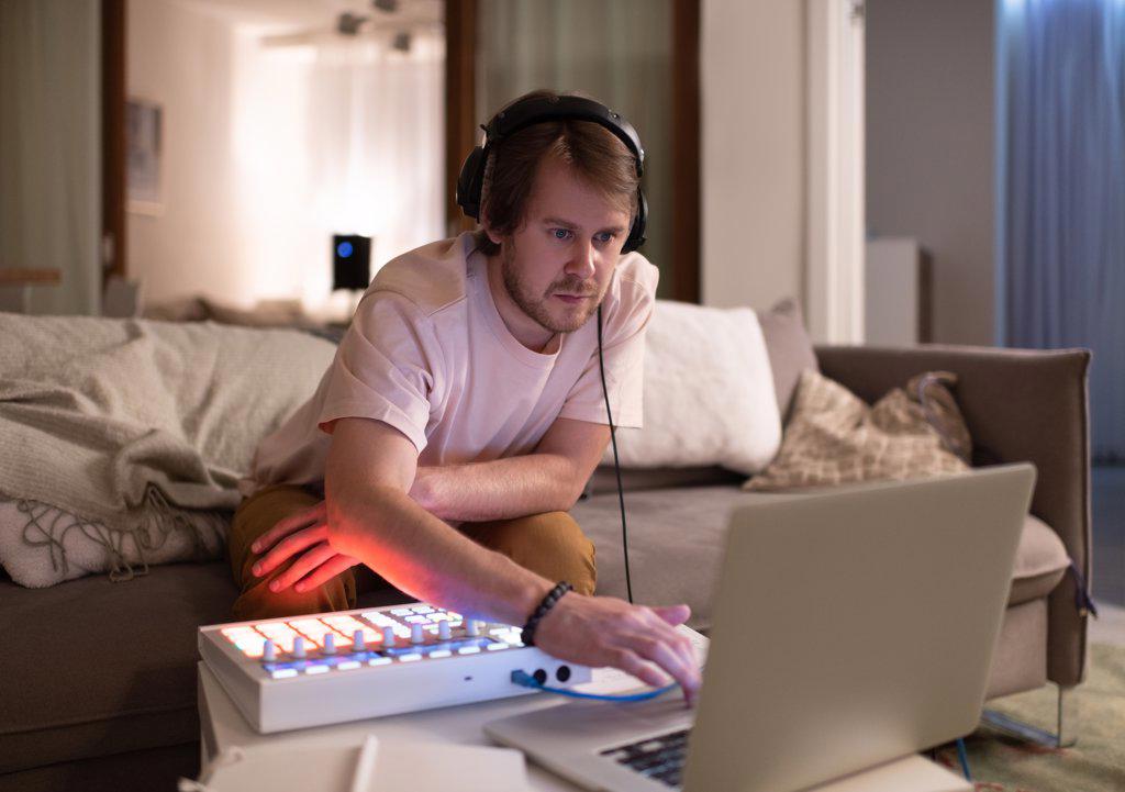 Male DJ using laptop on sofa