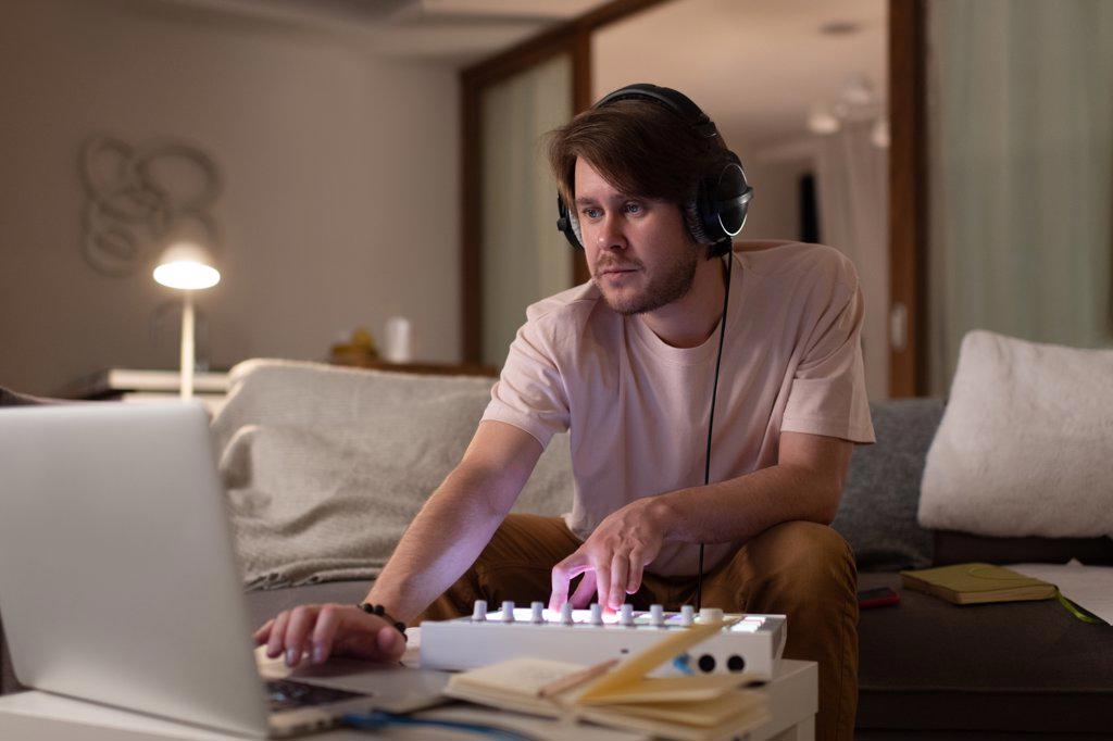 Male DJ mixing music on laptop at home