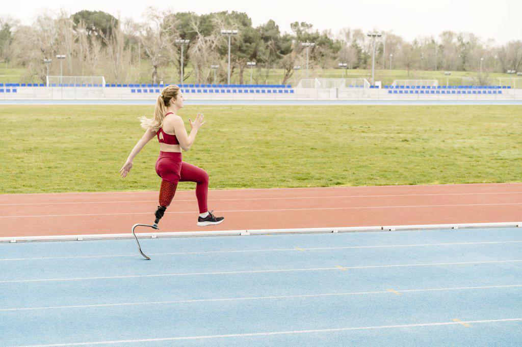 Strong handicapped athlete running on stadium