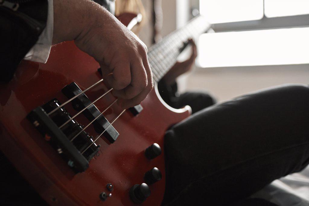 close-up of a man's fingers playing a bass guitar