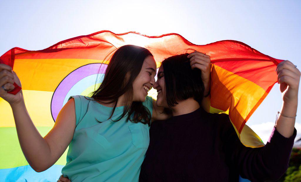 beautiful lesbian couple having fun in the street with a lgtb flag