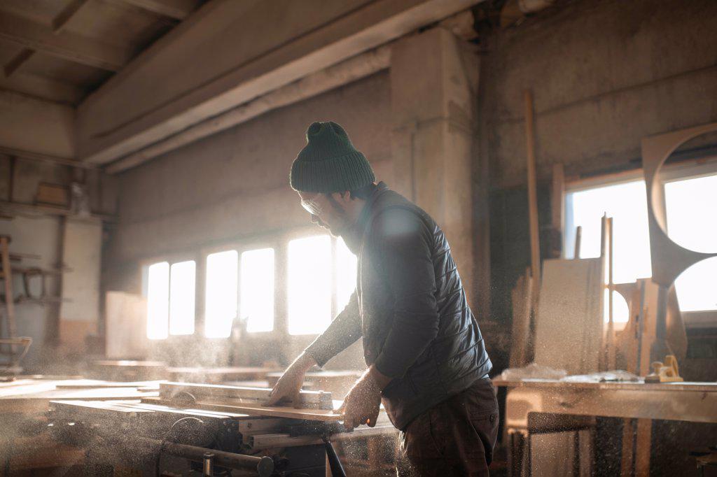 Male carpenter cutting wooden plank