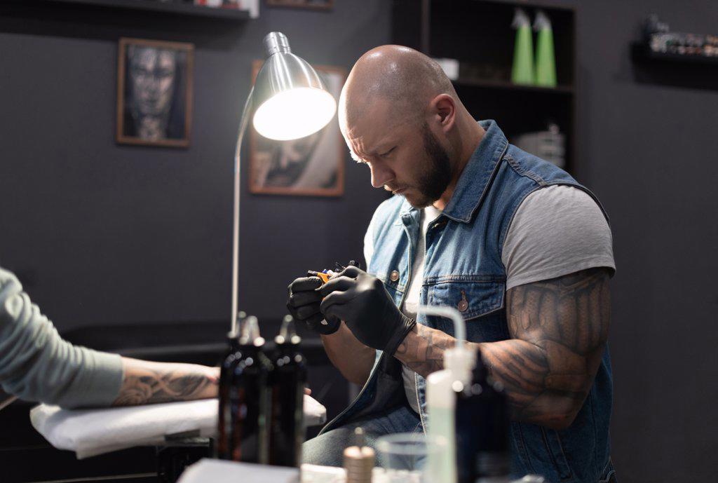 Tattoo artist working with client