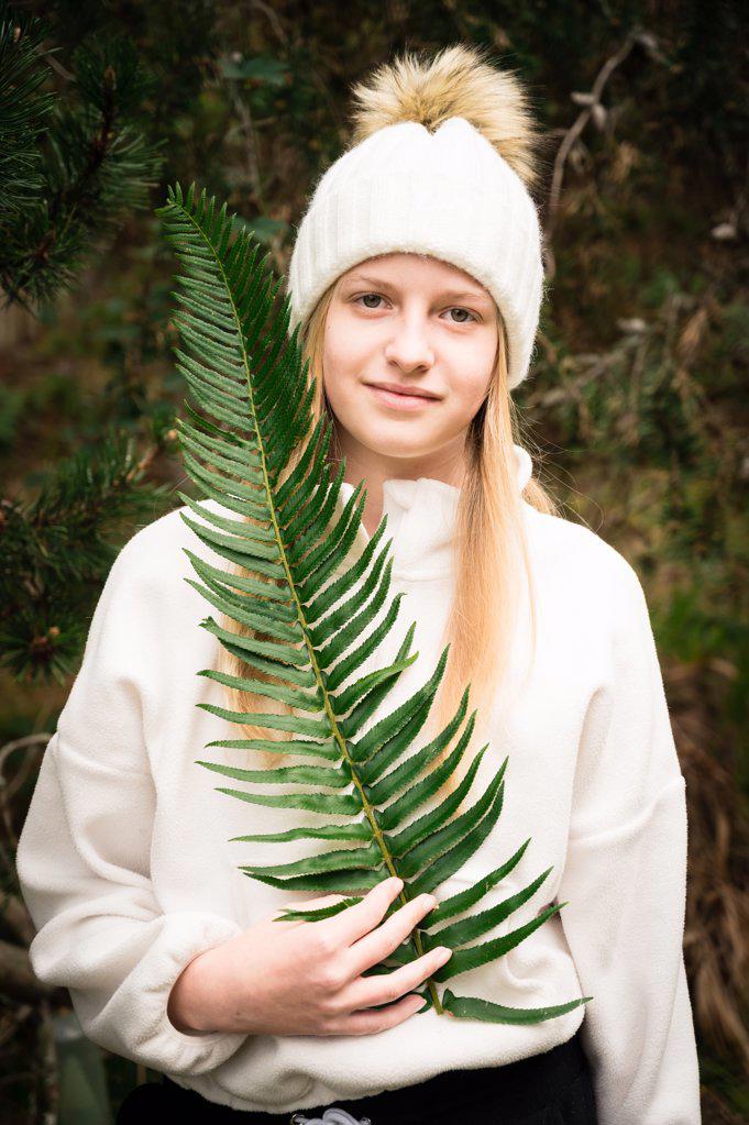 Young Girl In Woodland Setting Holding Large Fern Frond