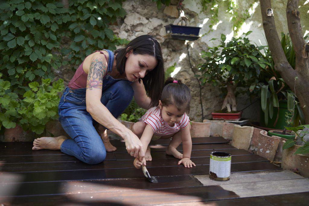 mother and daughter enjoy painting the wood floor together