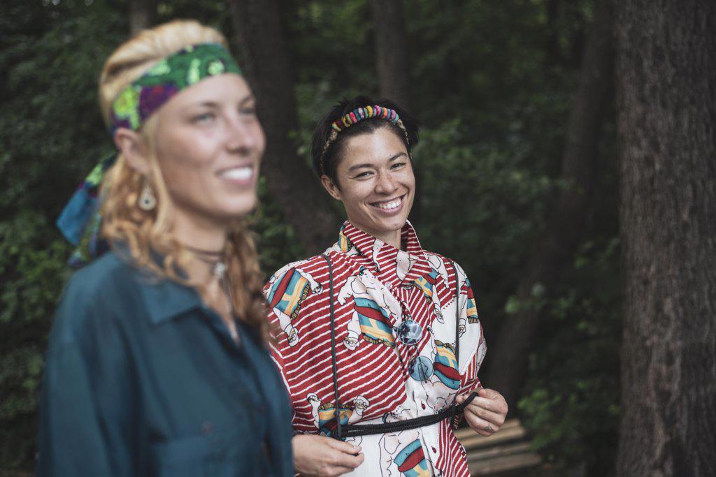 Mixed race women bohemian fashion in forrest together smiling