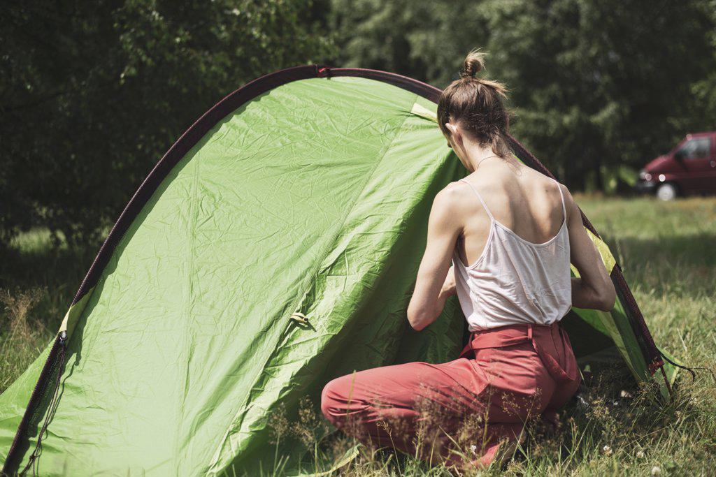 Healthy natural queer person zipping up a tent at festival in Poland