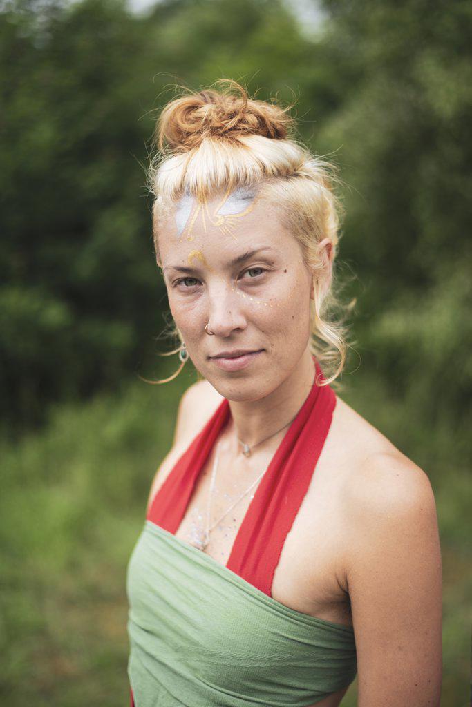 Beautiful empowered woman with facepaint in nature at festival