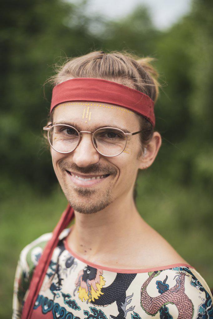 happy man at festival with glasses, facepaint and red bandana