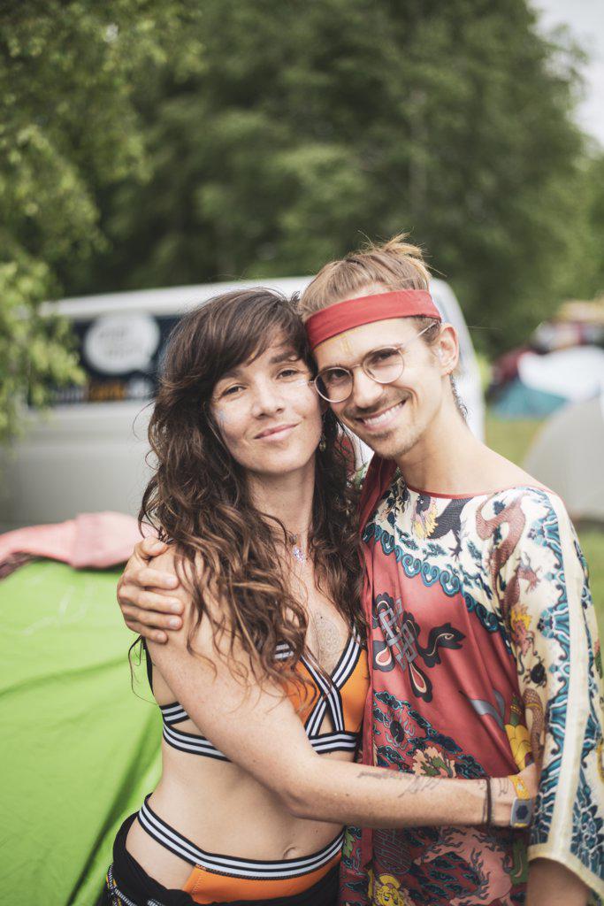 Two bohemian friends hugging smiling wearing funky clothes at festival