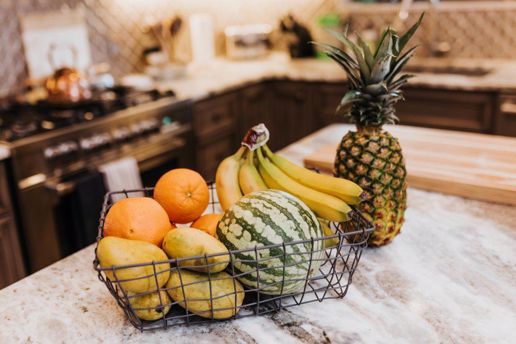 Fruit in a wire basket sitting on a kitchen counter