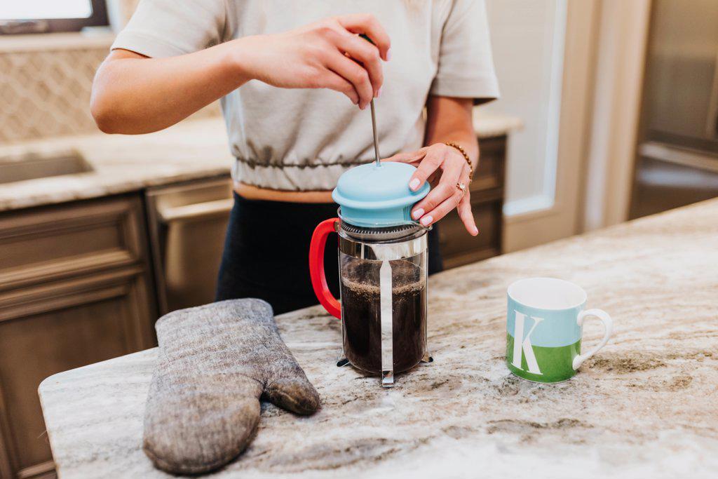 Woman makes french press coffee inside her home