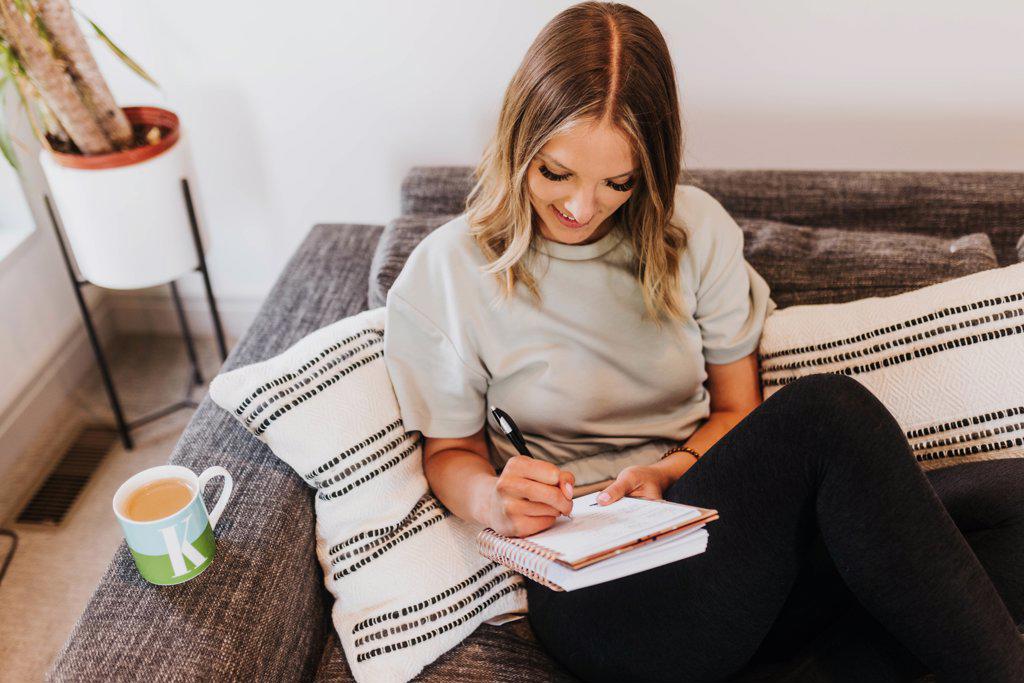 Above shot of woman writing in notebook from couch in living room