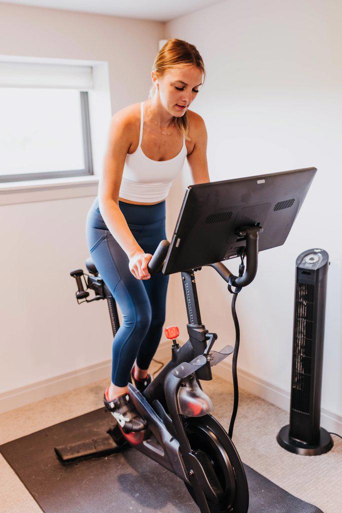 Close up of woman riding exercise bike in home gym