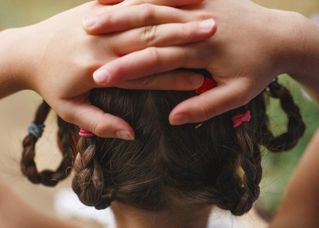 close-up of girl with braids and hands clasped behind her head