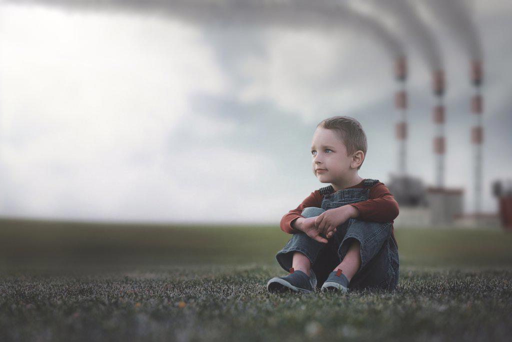 Little boy sitting on the grass environmental pollution concept.