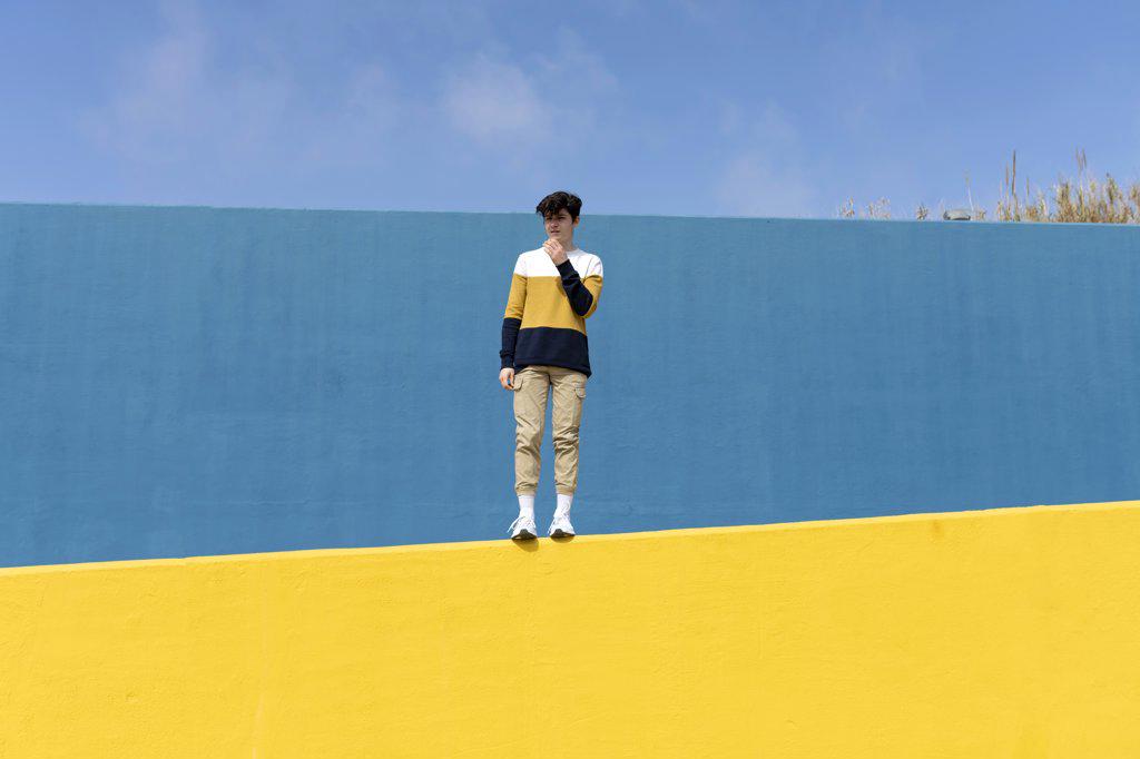Portrait of a teenage boy looking away against blue wall