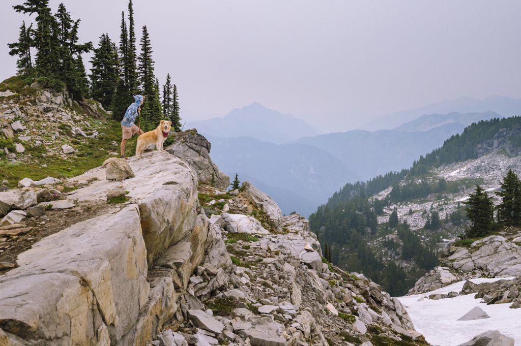 Hiker and dog standing on a cliff in the north cascade mountains