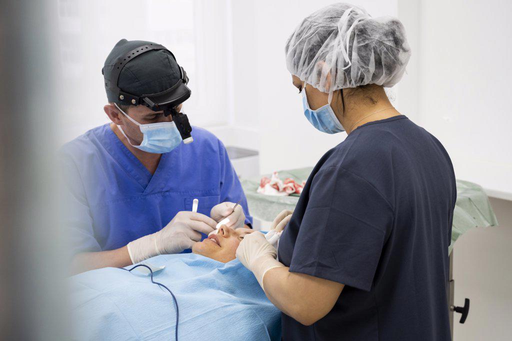Surgeon sutures the eyelid after plastic surgery operation