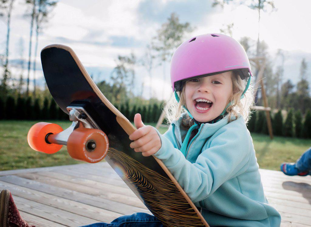 portrait of a girl laughing on a skateboard whilst playing at home