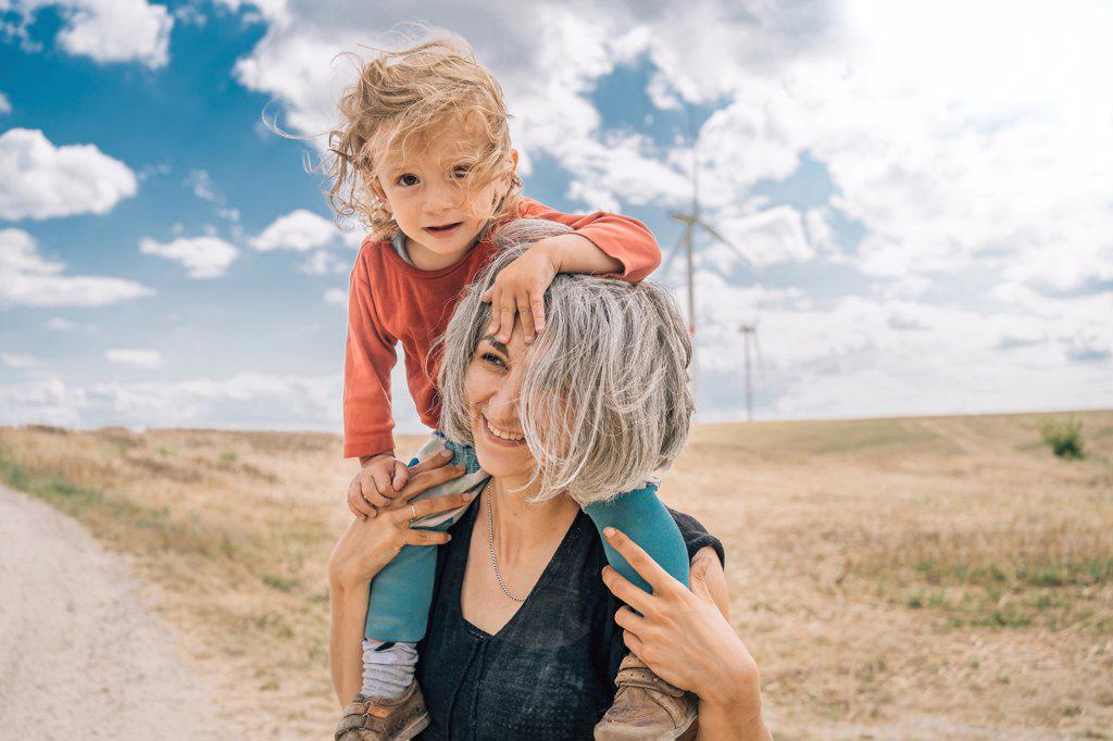 Mothe with toddler on her shoulders in field