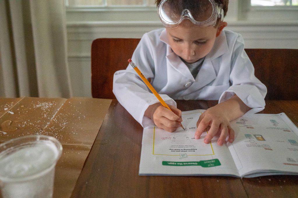 Young scientist in lab coat writing notes