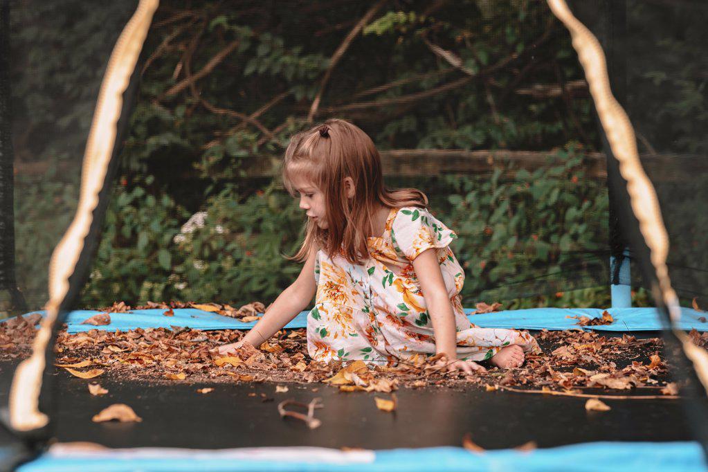 playing  in the fall leaves on her trampoline