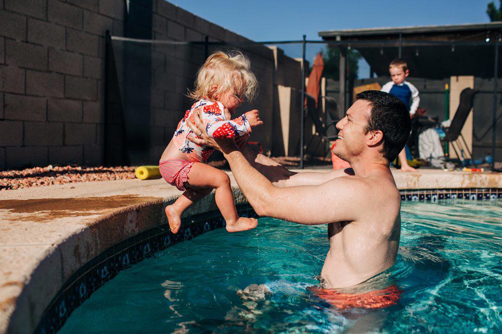 Father catches toddler daughter jumping into pool in summer