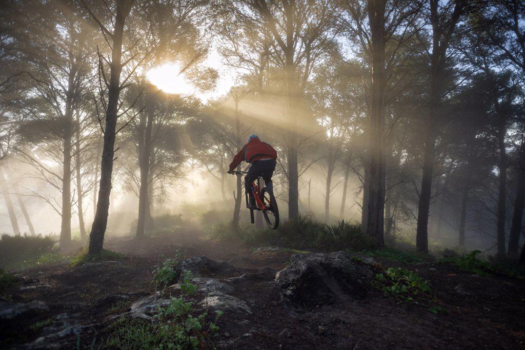 Young mountain biker jumps in a beatiful foggy morning. Spain