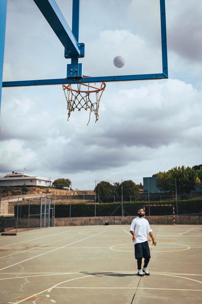 Young boy throwing a basketball to basket on a court