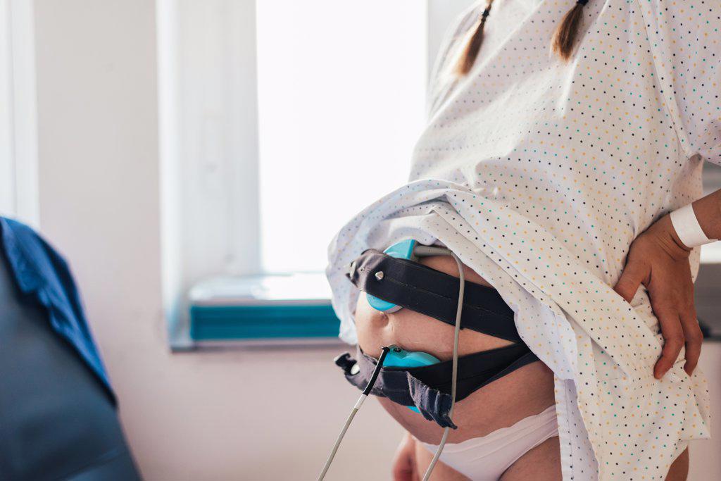 Belly of pregnant woman connected to pregnancy monitoring.