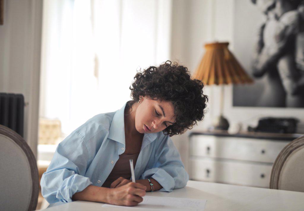 young woman writes on paper with pen at home