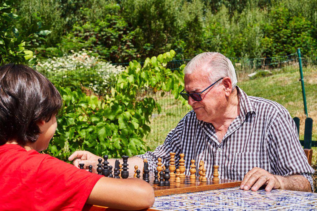 Grandfather and grandson playing chess in the garden