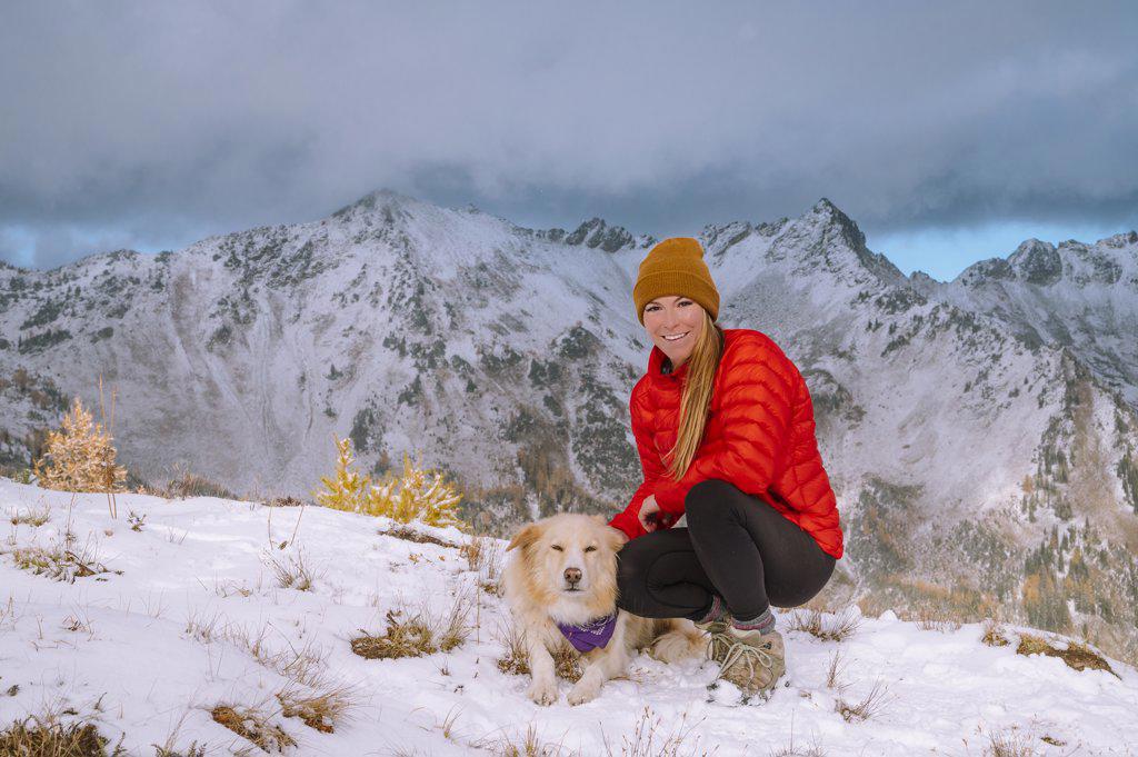 Female Hiker and Dog On a Snowy Mountain Ridge In The Cascades