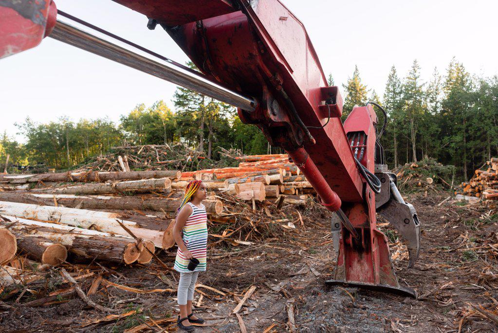 Girl stands under logging loader