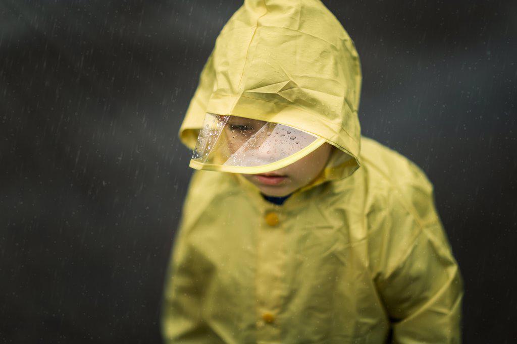 Portrait of toddler in yellow raincoat during rainfall