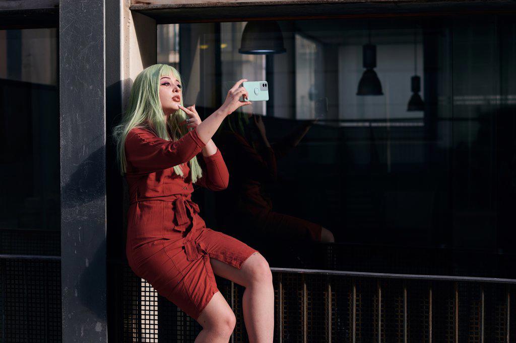 Alternative woman with green hair takes a selfie with her phone