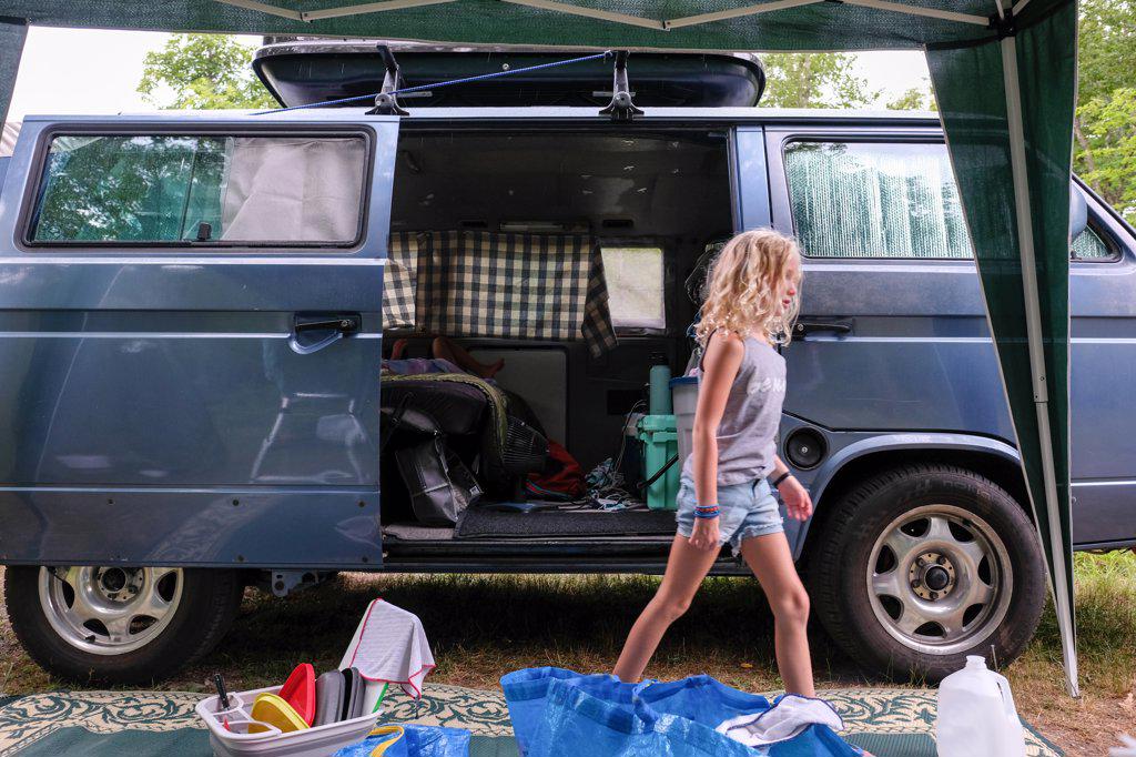 little girl walking away from camping van while camping in woods