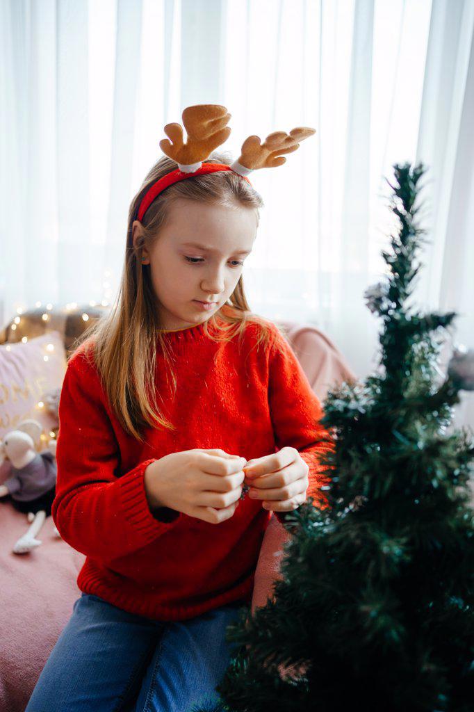 girl in a christmas costume decorates the christmas tree