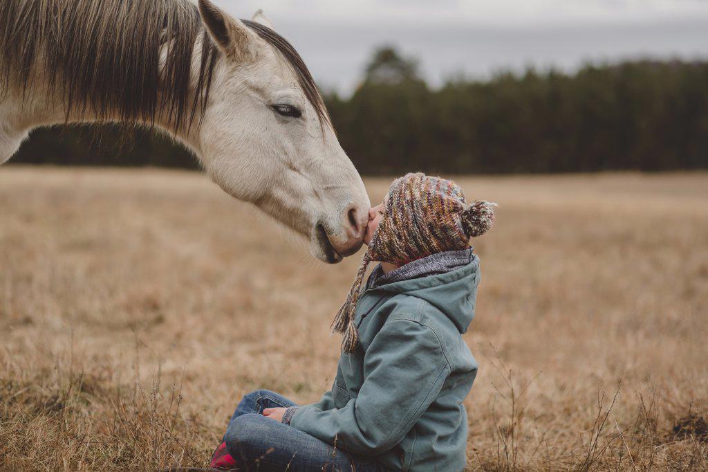 teen girl sitting in front of horse kissing nose